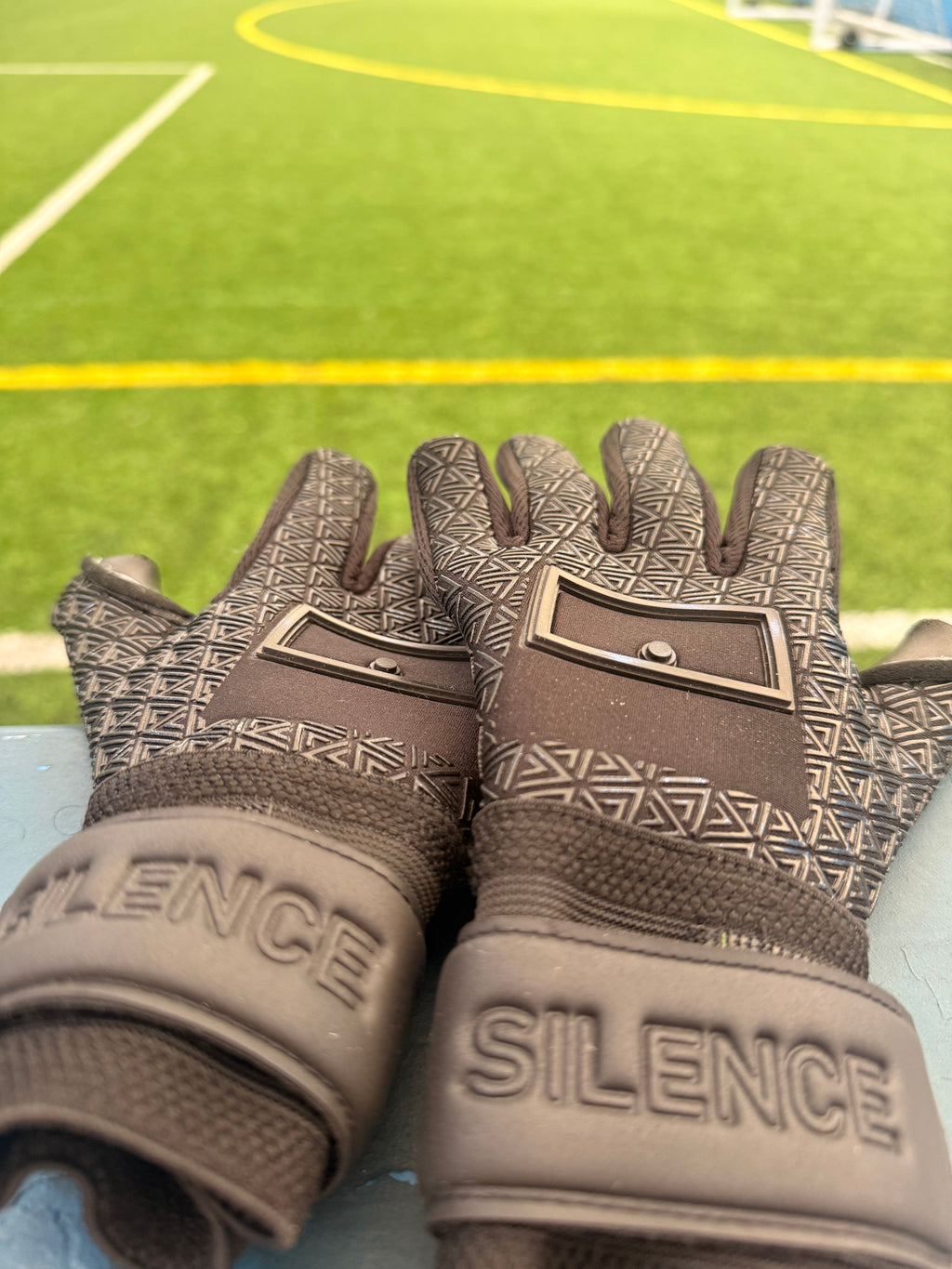 Foundation 01 Goalkeeper Gloves on a bench with a soccer field in the background